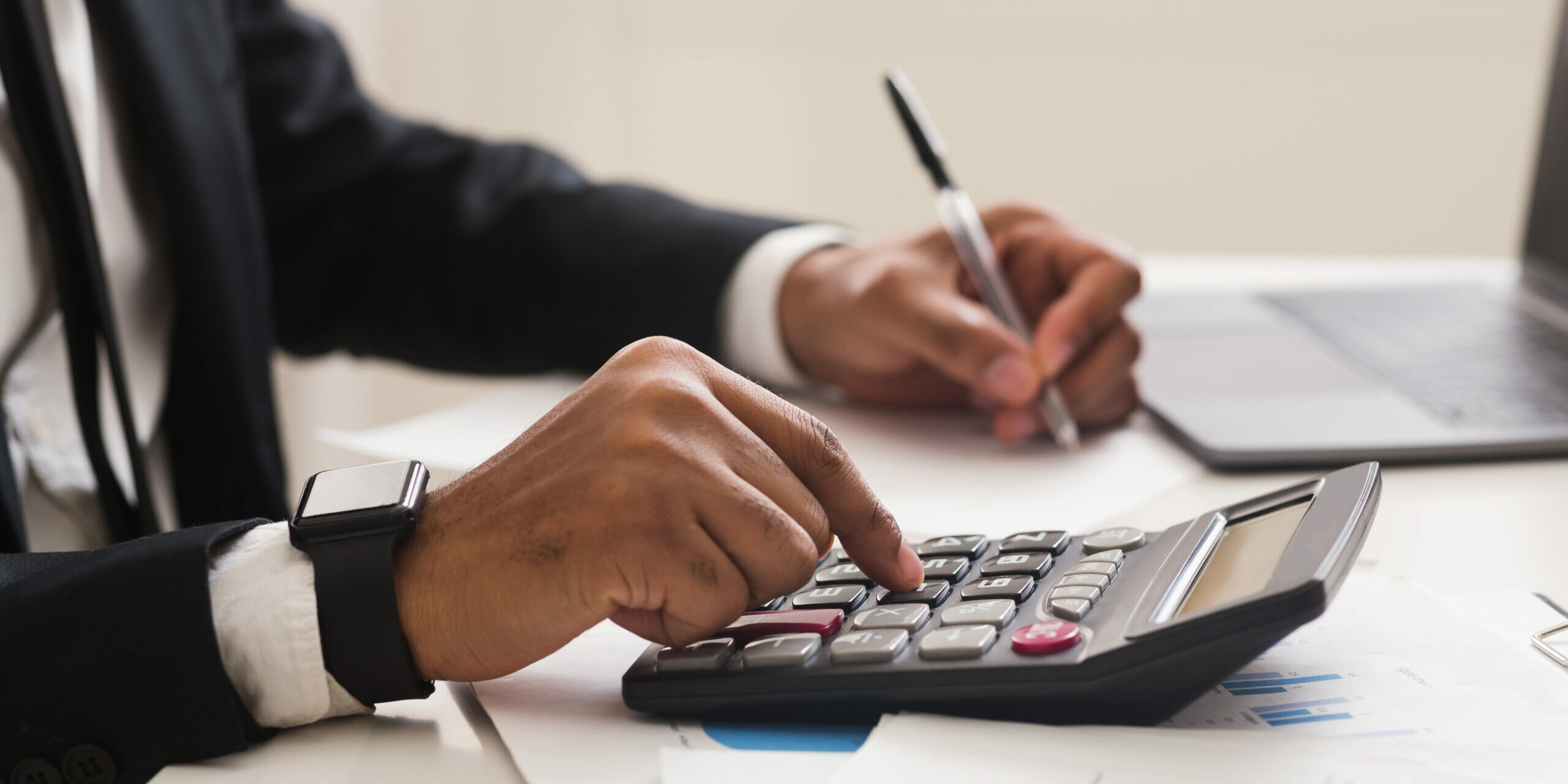 Accounting consulting concept. Businessman checking on incomes in office, using calculator, taking notes, cropped