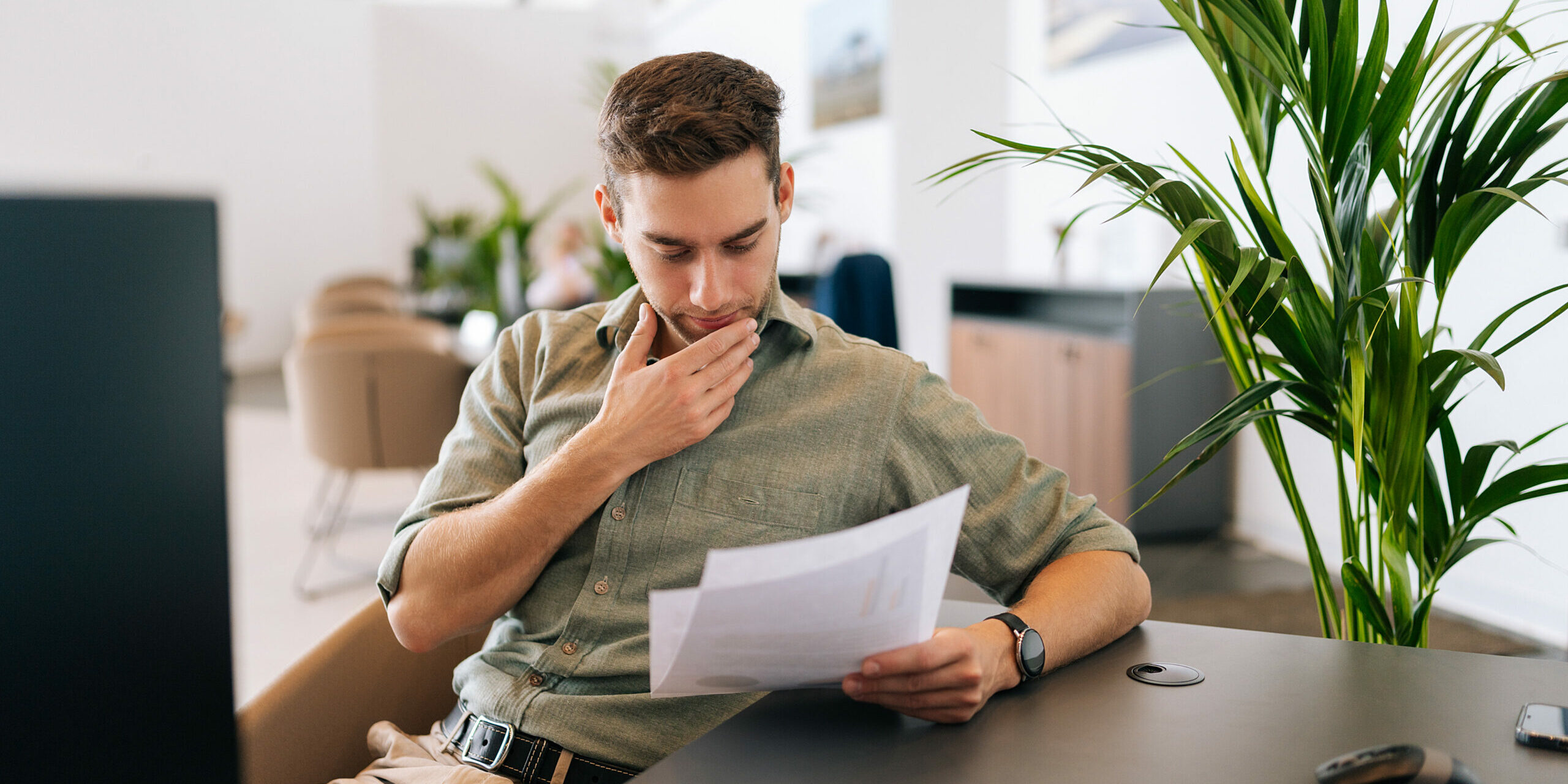 Portrait of focused male client reading contract for real estate property purchase. Thoughtful man reading terms of conditions of document, making decision about house purchase or financial investment